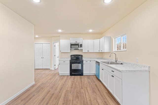 kitchen featuring light wood-type flooring, light countertops, white cabinets, stainless steel appliances, and a sink