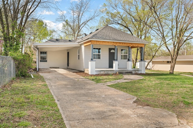 view of front of house featuring covered porch, fence, a front lawn, driveway, and roof with shingles