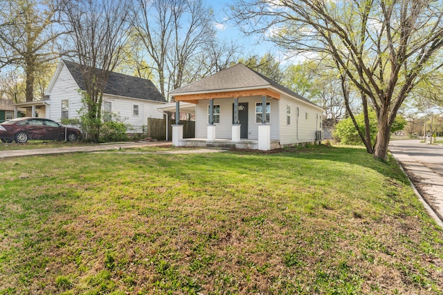 bungalow-style home with a front yard, fence, a shingled roof, and covered porch
