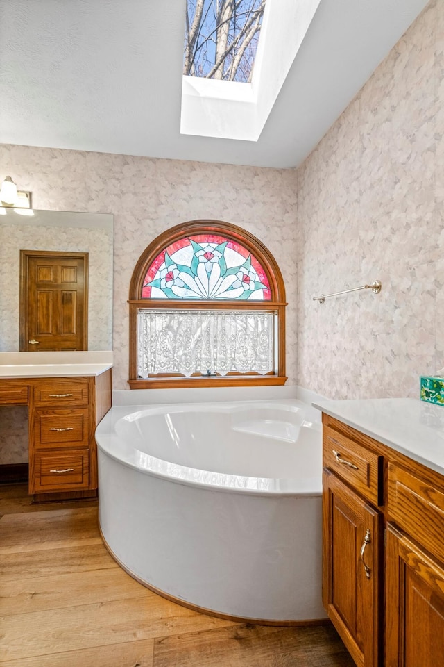 3131 E Southern Hills Blvd, Springfield, MO 65804 - bathroom with a tub to relax in, vanity, a skylight, wood finished floors, and wallpapered walls