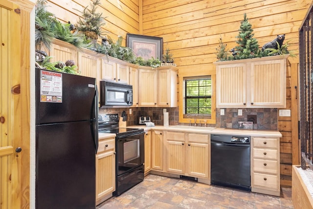 kitchen with wooden walls, black appliances, decorative backsplash, a sink, and light brown cabinetry