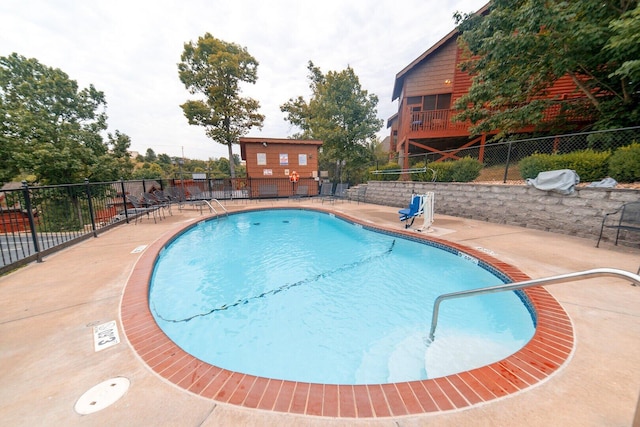 community pool with a patio area and fence