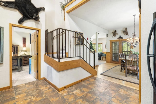 foyer with baseboards, an inviting chandelier, stairway, visible vents, and stone tile floors