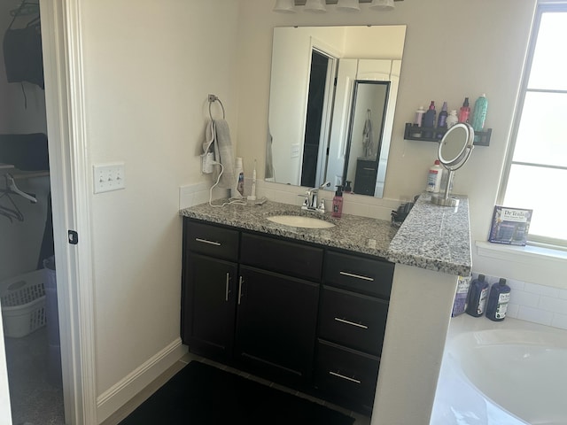 full bath featuring vanity, baseboards, and a tub