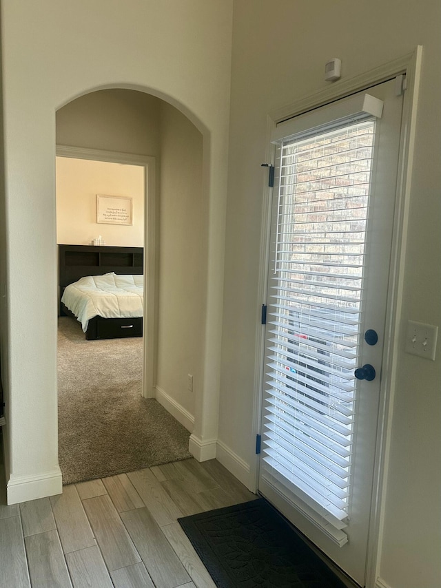 hallway with baseboards, arched walkways, and wood finish floors