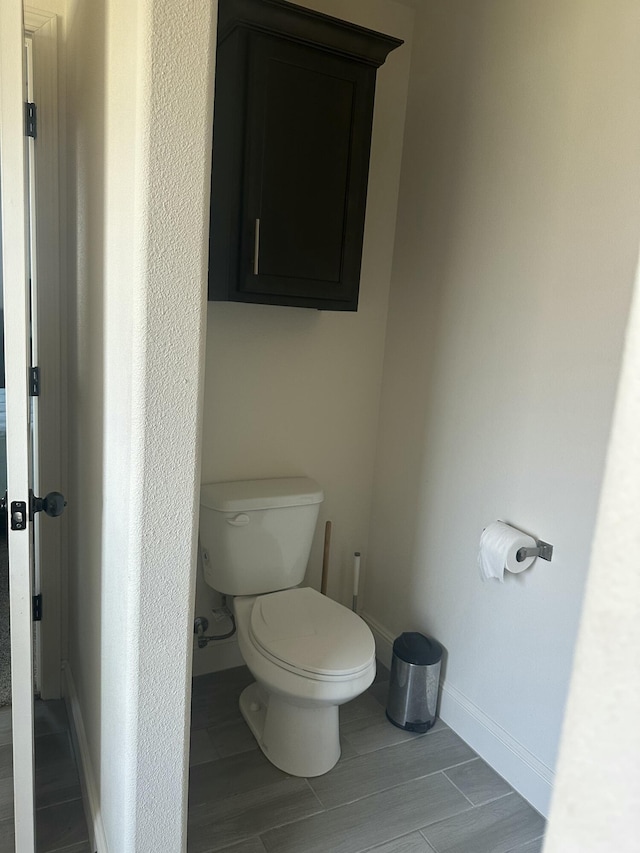 bathroom featuring toilet, baseboards, and wood tiled floor