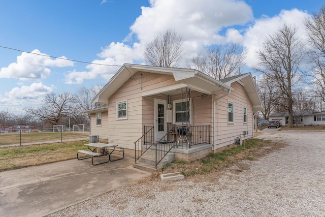 bungalow-style home with cooling unit and fence