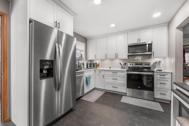 kitchen featuring tasteful backsplash, white cabinets, a sink, light countertops, and appliances with stainless steel finishes