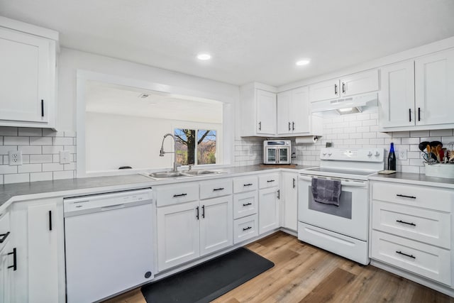 kitchen featuring white appliances, white cabinetry, under cabinet range hood, a sink, and decorative backsplash