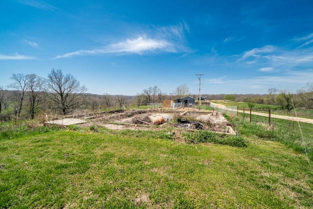 view of yard with a rural view, fence, and an outdoor structure