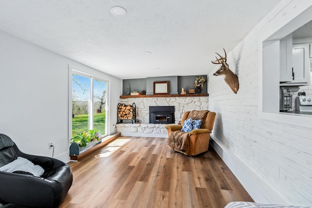 living area featuring a textured ceiling, wood finished floors, a fireplace, and baseboards