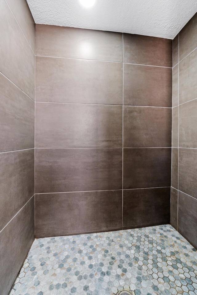 bathroom with tiled shower and a textured ceiling