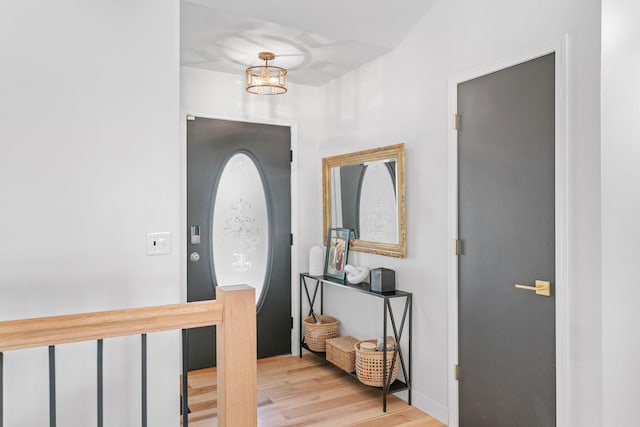 entryway with wood finished floors and an inviting chandelier