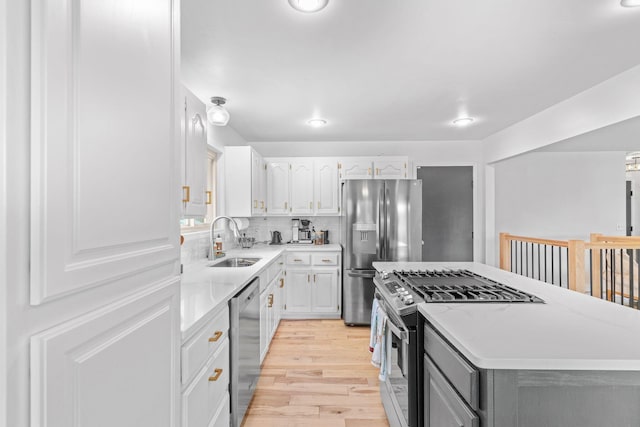 kitchen featuring light wood-style floors, a kitchen island, appliances with stainless steel finishes, light countertops, and a sink