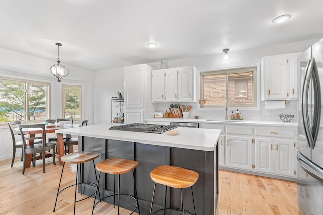 kitchen featuring white cabinets, a sink, light countertops, appliances with stainless steel finishes, and a breakfast bar area