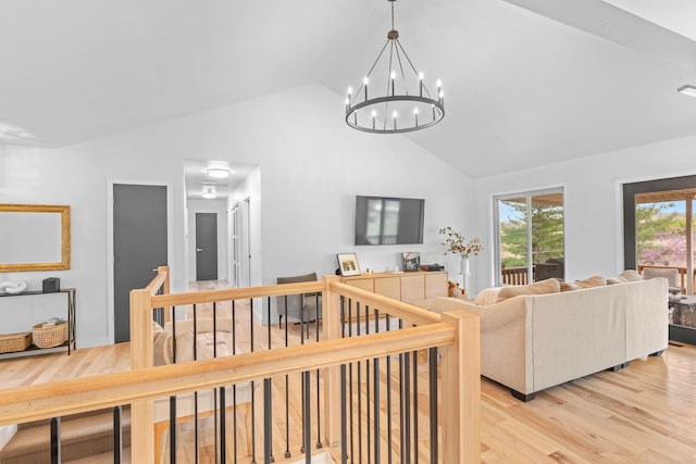 living area featuring high vaulted ceiling, light wood-style floors, and a chandelier