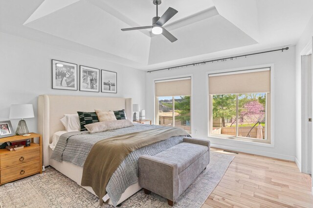 bedroom with a raised ceiling, wood finished floors, a ceiling fan, and visible vents