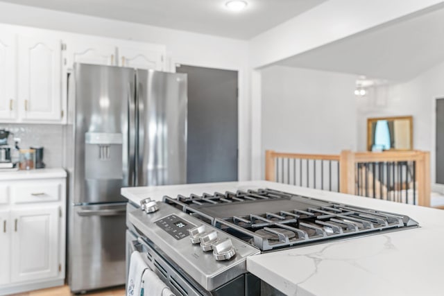 kitchen featuring stainless steel appliances, light stone countertops, and white cabinetry