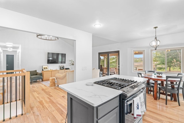 kitchen with gray cabinets, light wood finished floors, stainless steel gas stove, and a healthy amount of sunlight