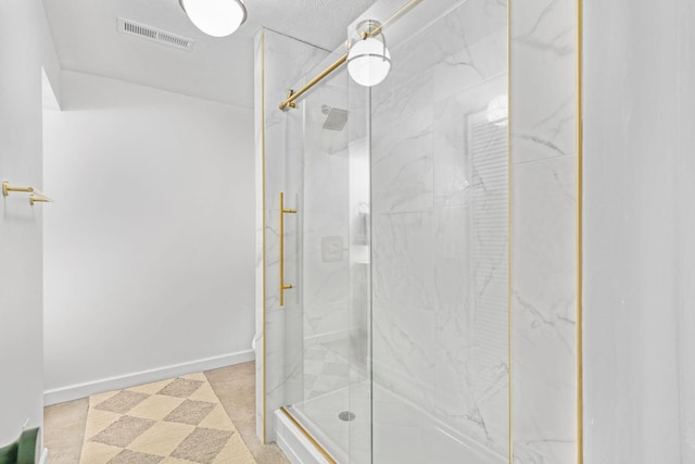 bathroom featuring a marble finish shower, baseboards, and visible vents