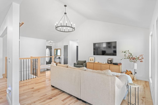 living area featuring wood finished floors, high vaulted ceiling, a notable chandelier, and baseboards