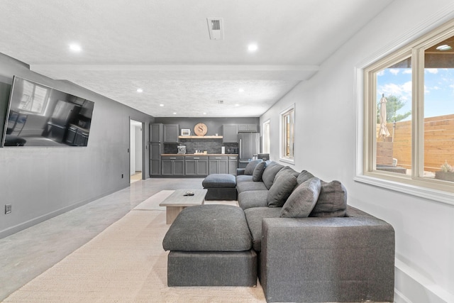 living area with visible vents, baseboards, recessed lighting, and finished concrete floors