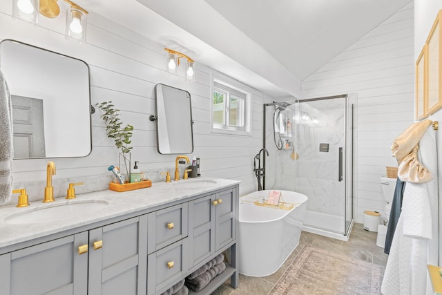 bathroom with a sink, a marble finish shower, double vanity, and vaulted ceiling