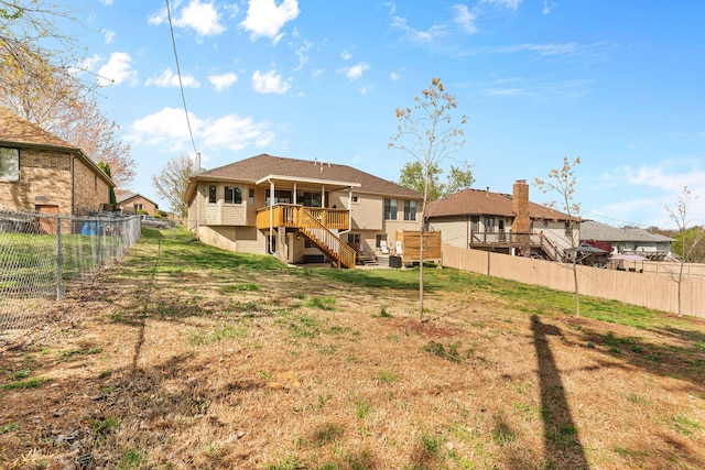 rear view of property featuring a lawn, a fenced backyard, a deck, and stairway