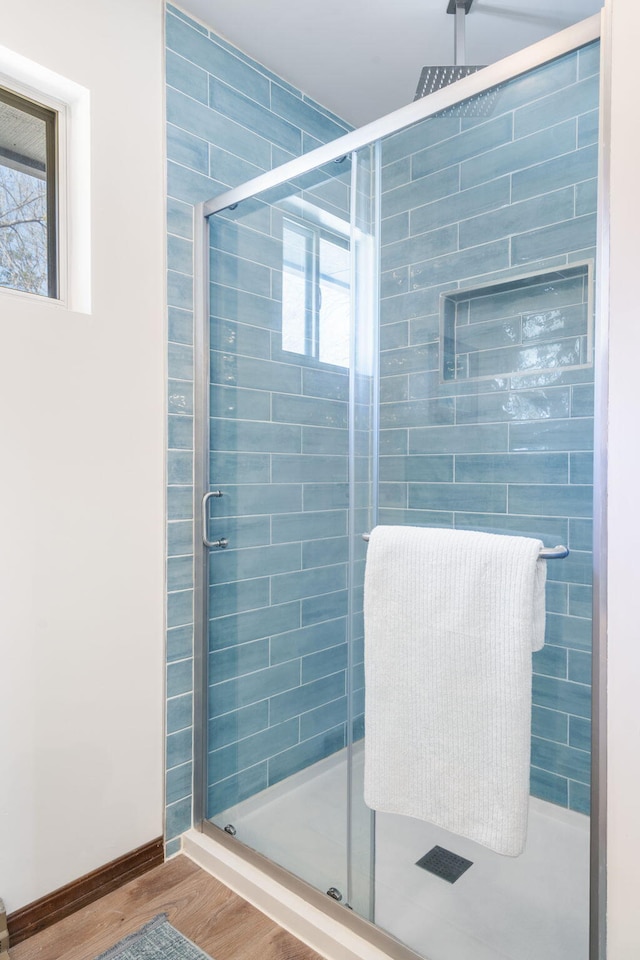 bathroom with baseboards, a stall shower, and wood finished floors