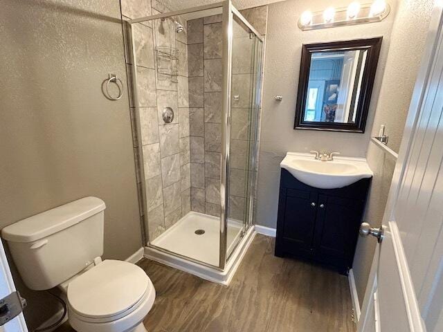 full bath featuring a shower stall, baseboards, toilet, and wood finished floors
