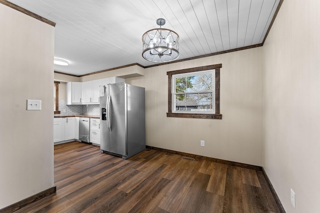kitchen with crown molding, white cabinetry, a chandelier, appliances with stainless steel finishes, and baseboards