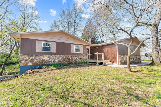view of front facade featuring a front yard, a deck, and stone siding