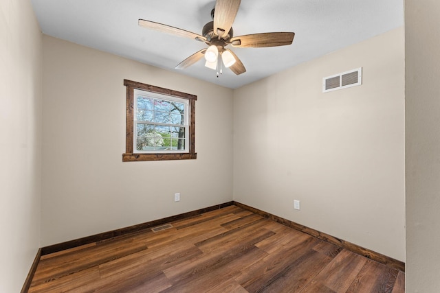spare room with dark wood-type flooring, ceiling fan, baseboards, and visible vents