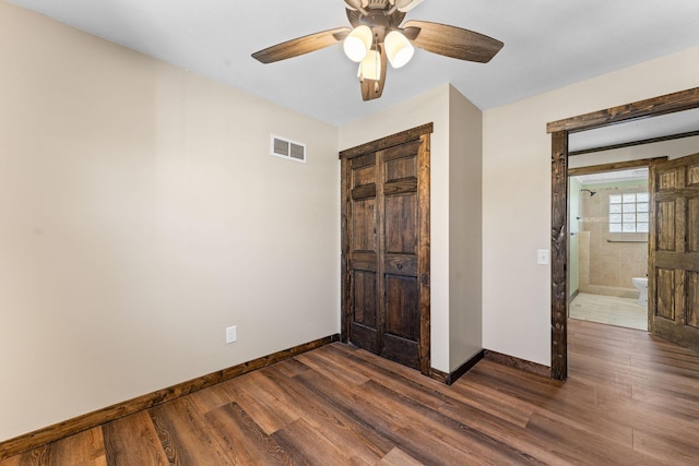 unfurnished bedroom with a closet, baseboards, dark wood-style floors, visible vents, and ceiling fan