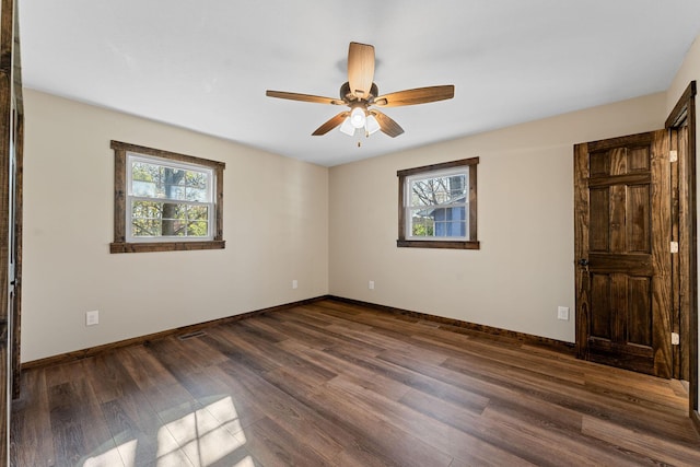 empty room with ceiling fan, baseboards, and dark wood finished floors