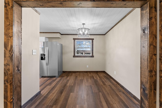 unfurnished dining area with a chandelier, ornamental molding, baseboards, and dark wood finished floors