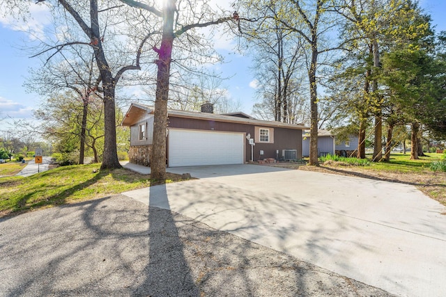 view of front of property featuring central AC, a chimney, an attached garage, and concrete driveway