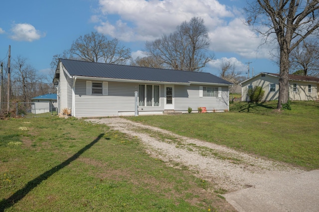 view of front of property featuring fence, metal roof, a front yard, and driveway