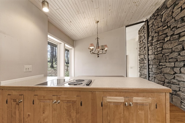 kitchen featuring stainless steel electric stovetop, wood finished floors, an inviting chandelier, and light countertops