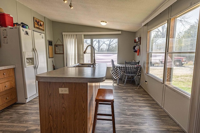 15601 County Road 281, Wheatland, MO 65779 - kitchen with white fridge with ice dispenser, a kitchen bar, dark wood finished floors, a textured ceiling, and vaulted ceiling