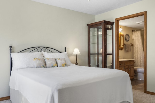 carpeted bedroom featuring baseboards and ensuite bath