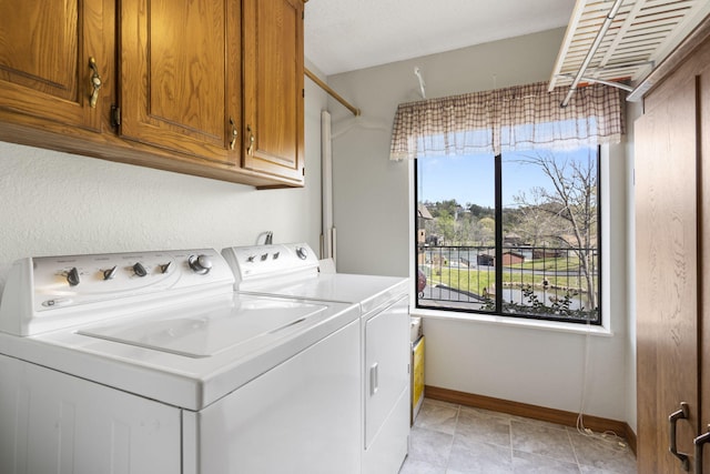clothes washing area featuring separate washer and dryer, baseboards, and cabinet space