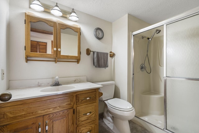 bathroom featuring a shower stall, a textured ceiling, vanity, toilet, and tile patterned floors