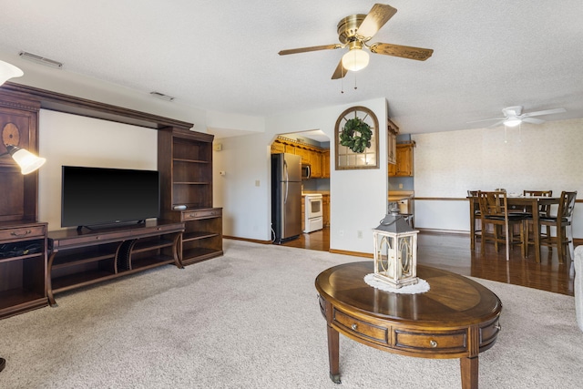 carpeted living room with visible vents, baseboards, and a ceiling fan