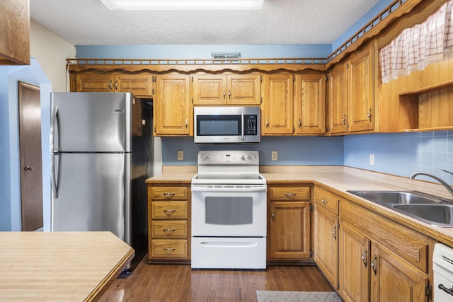 kitchen featuring light countertops, a textured ceiling, appliances with stainless steel finishes, and a sink