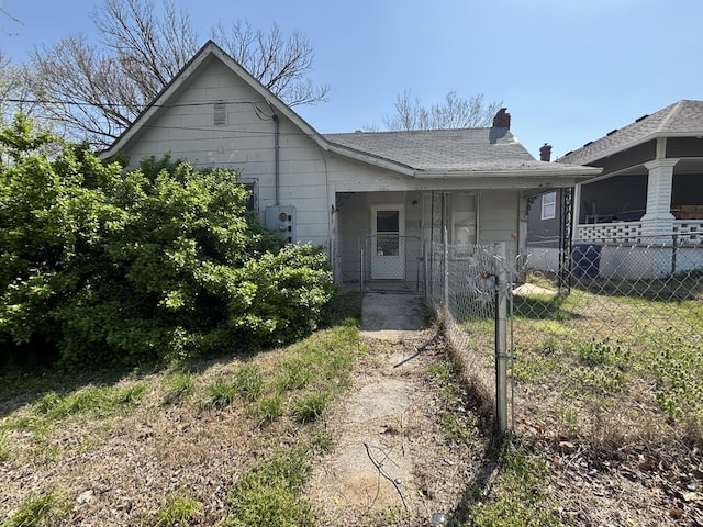 view of front of house with a chimney, a shingled roof, fence, and a gate