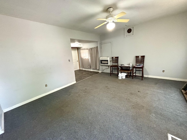 interior space with dark colored carpet, a ceiling fan, baseboards, and heating unit