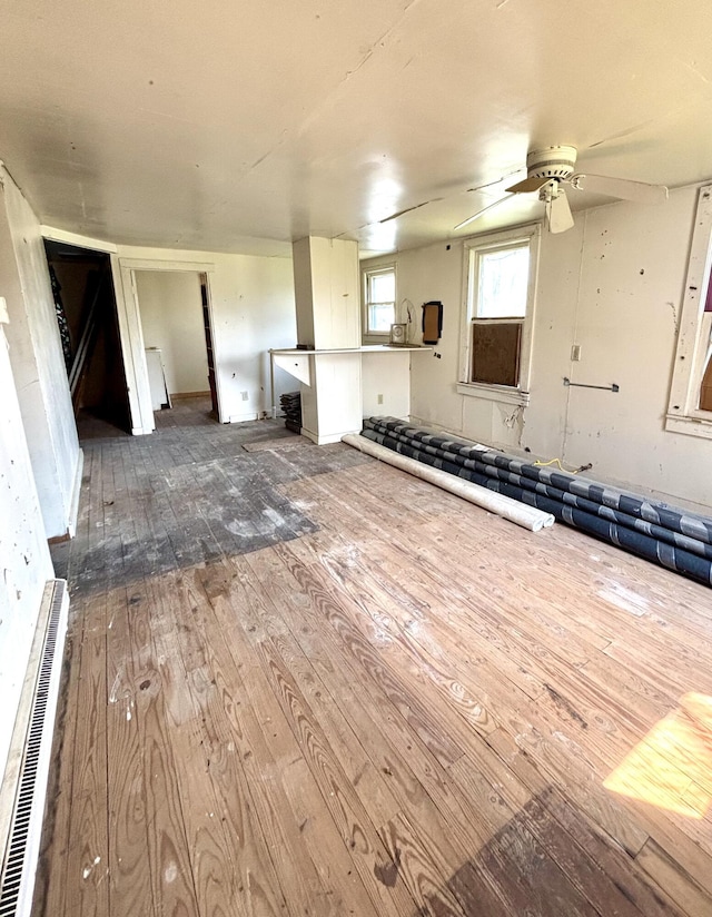 unfurnished living room with wood-type flooring, ceiling fan, and visible vents