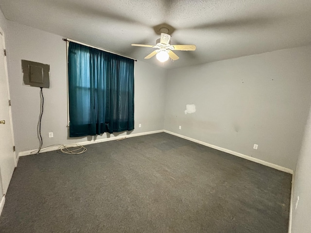empty room featuring ceiling fan, dark colored carpet, and baseboards