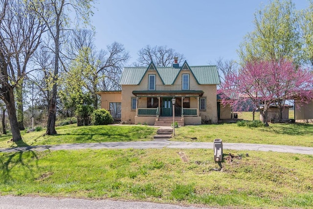 view of front of property featuring a porch, metal roof, a front lawn, and stucco siding